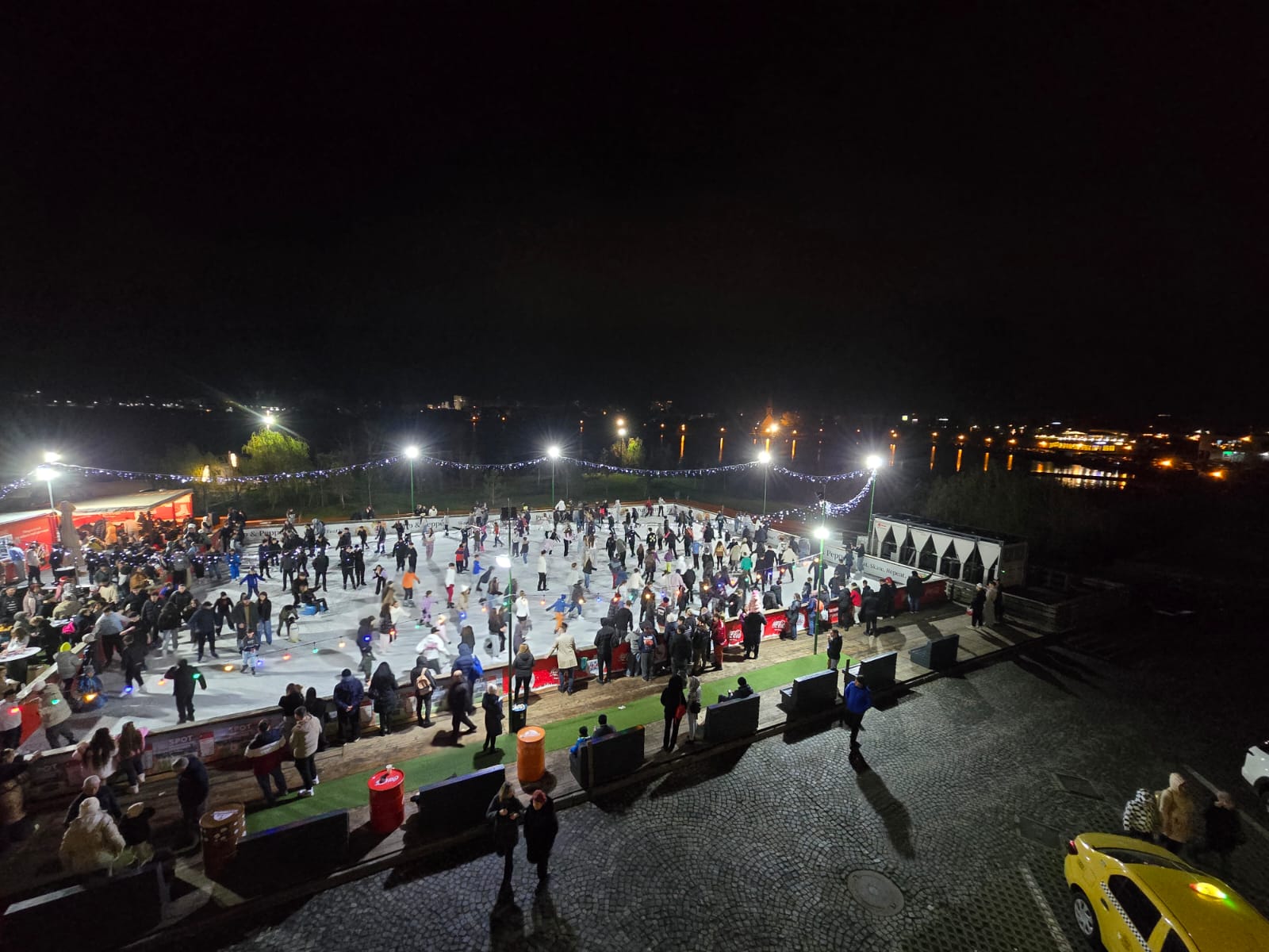 Patinoar în aer liber, seara, plin de patinatori